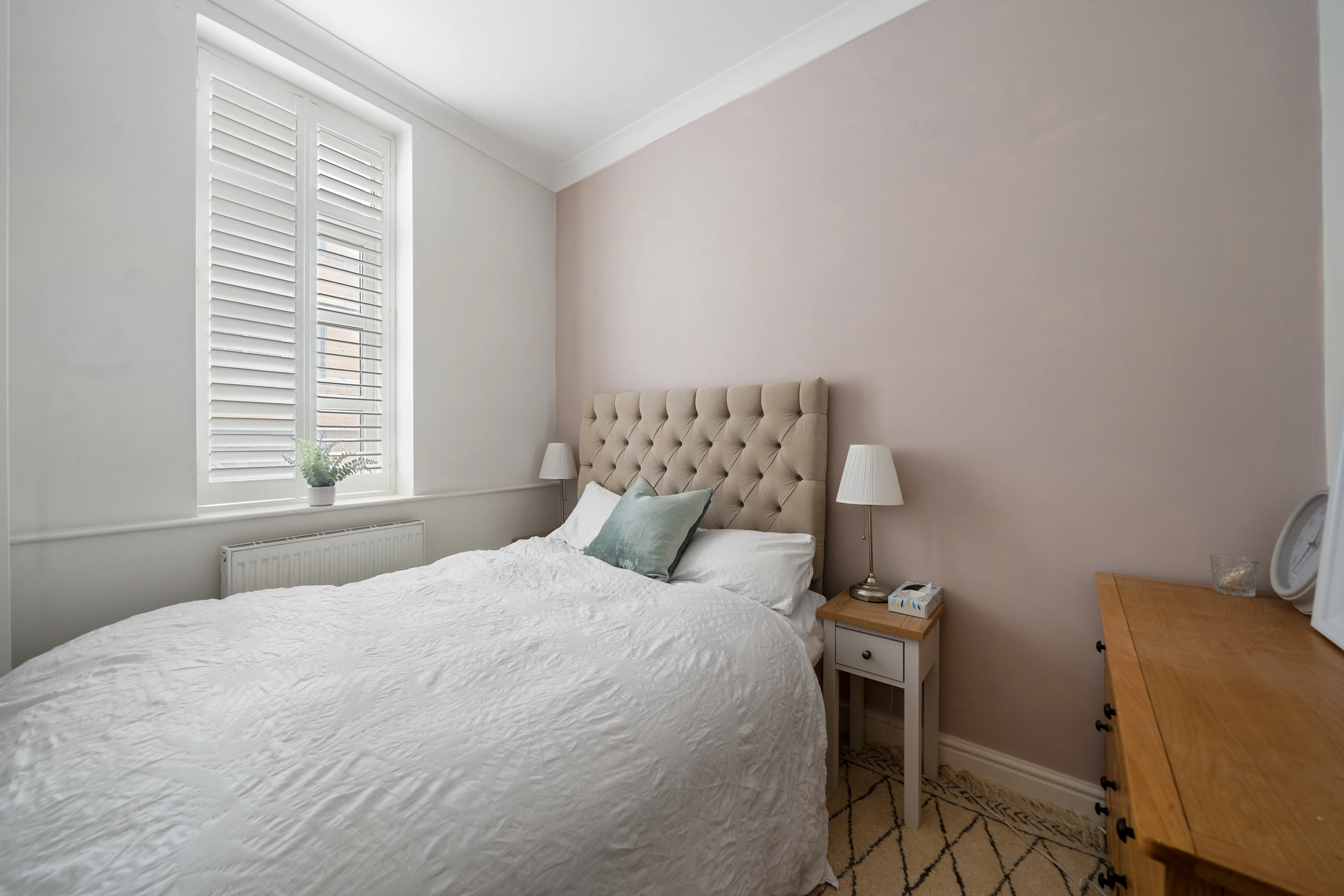 Bedroom with a double bed, pink bedding and dressing table