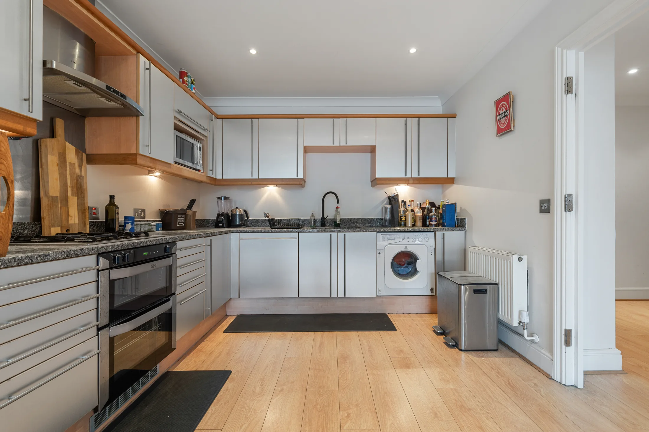 Fitted kitchen with white cabinetry, timber worktops and integrated appliances
