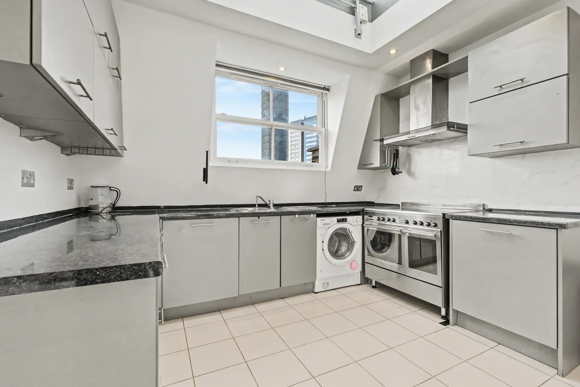 Kitchen with grey cabinetry, a range cooker and a skylight