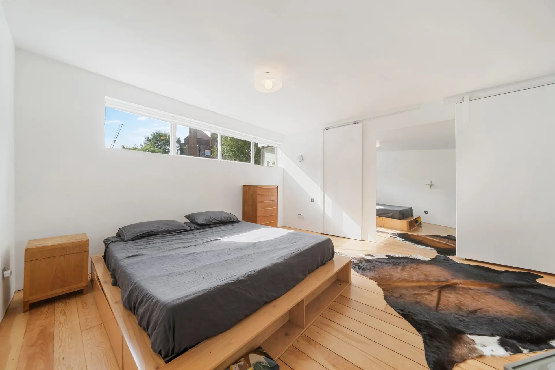 Bedroom with a raised timber platform bed, wide window and sliding doors