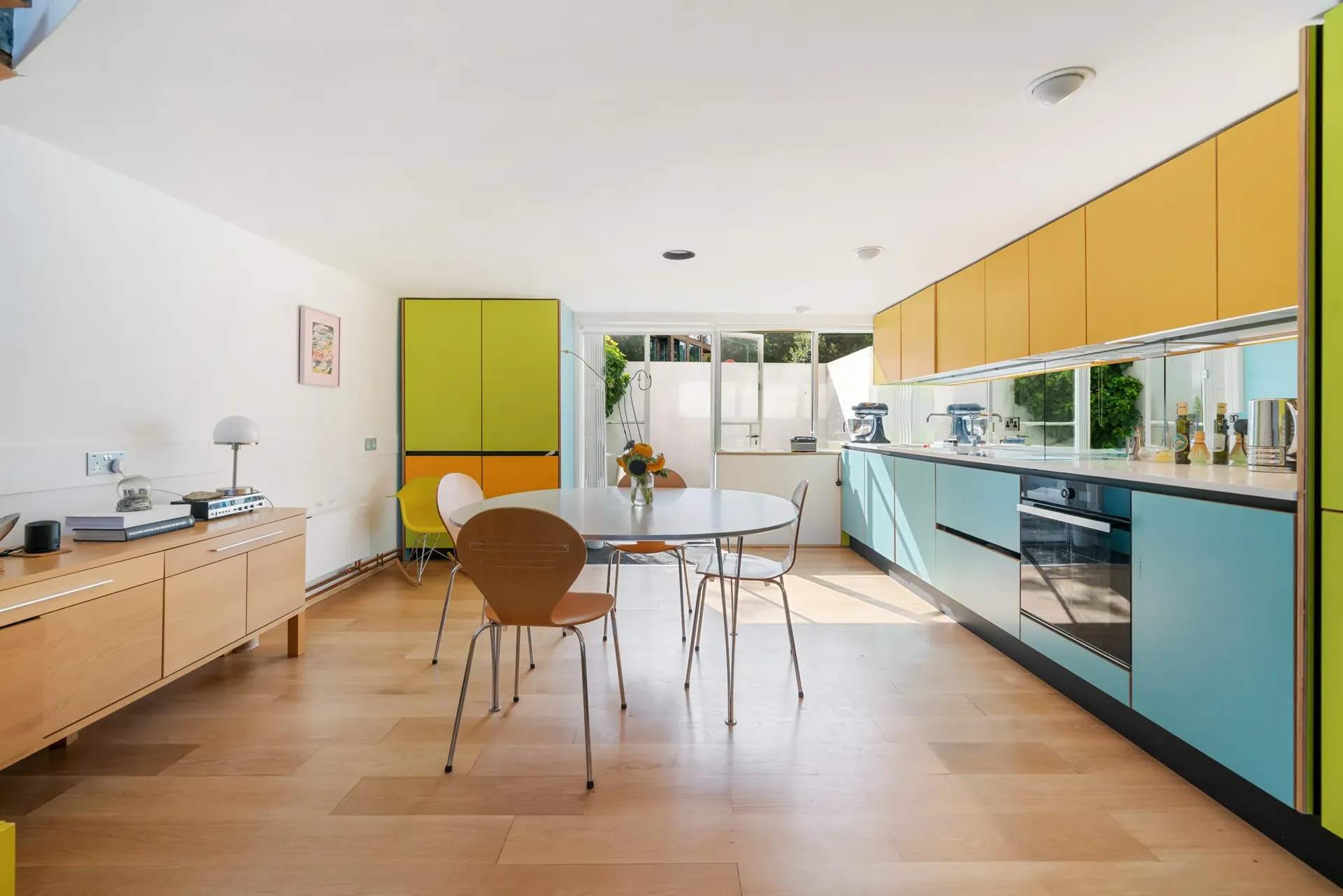 Kitchen and dining area with colourful fitted units and doors to the patio