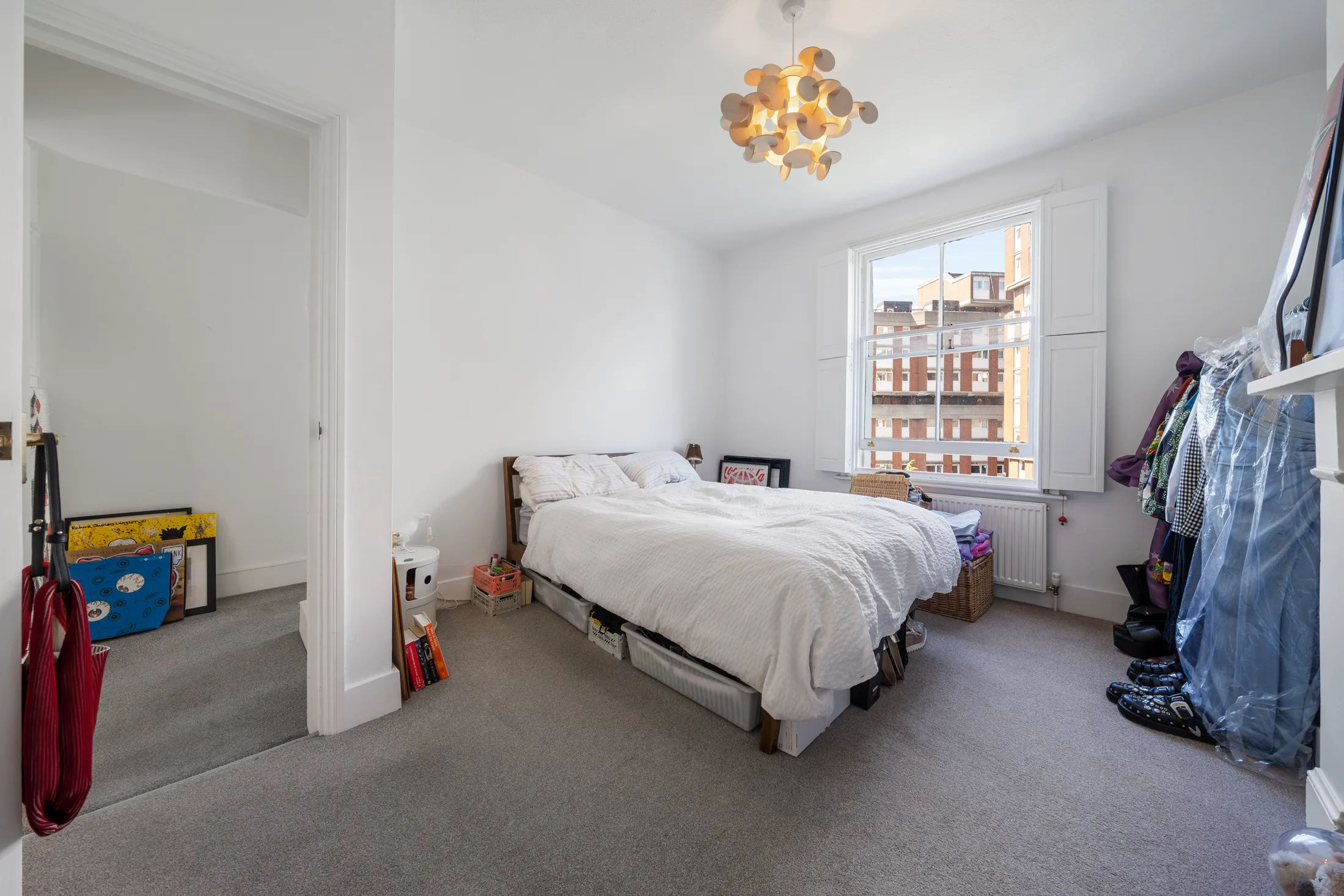 Bedroom with a white bed, fireplace and view through the window