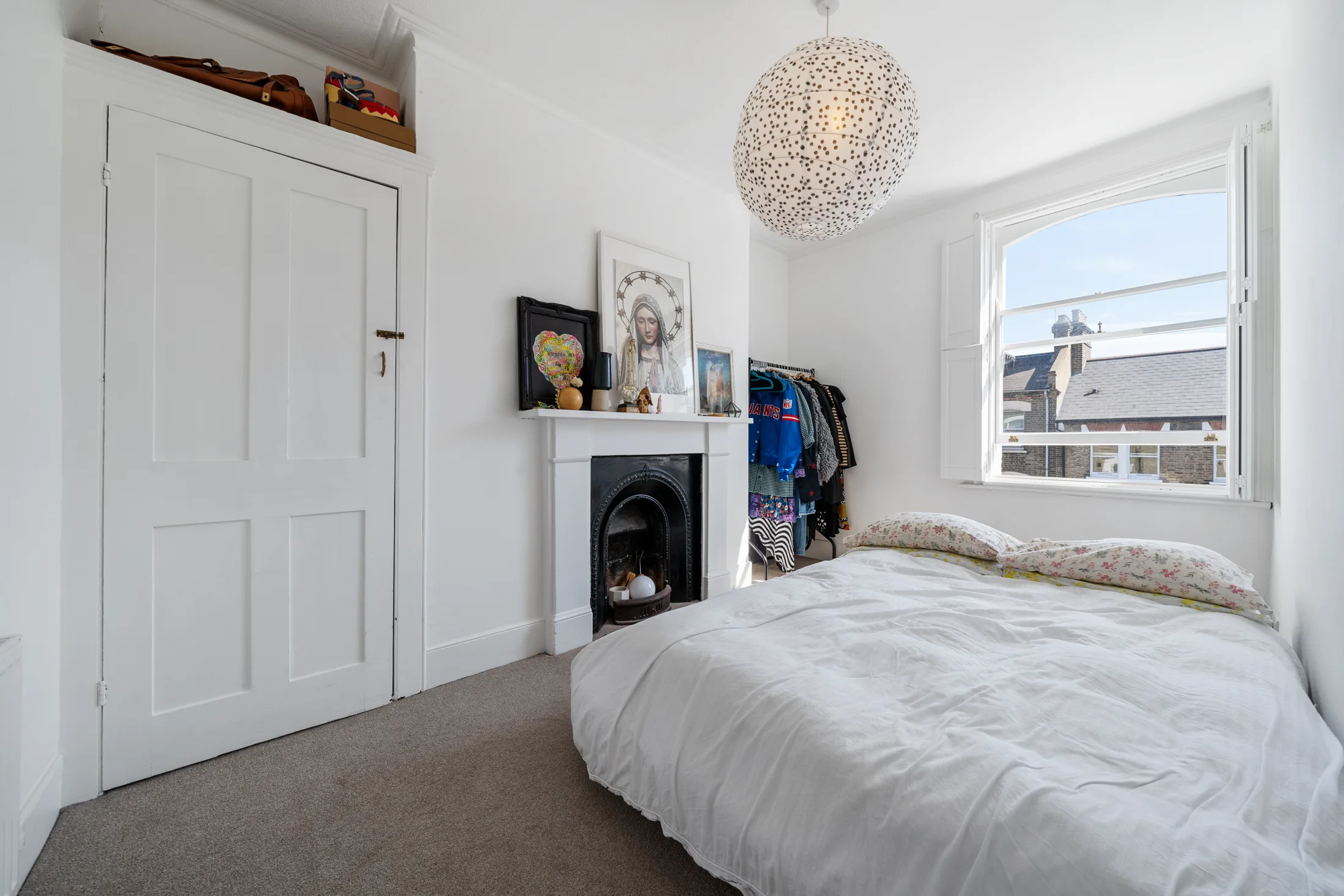 Bedroom with a white bed, fireplace and built-in wardrobe