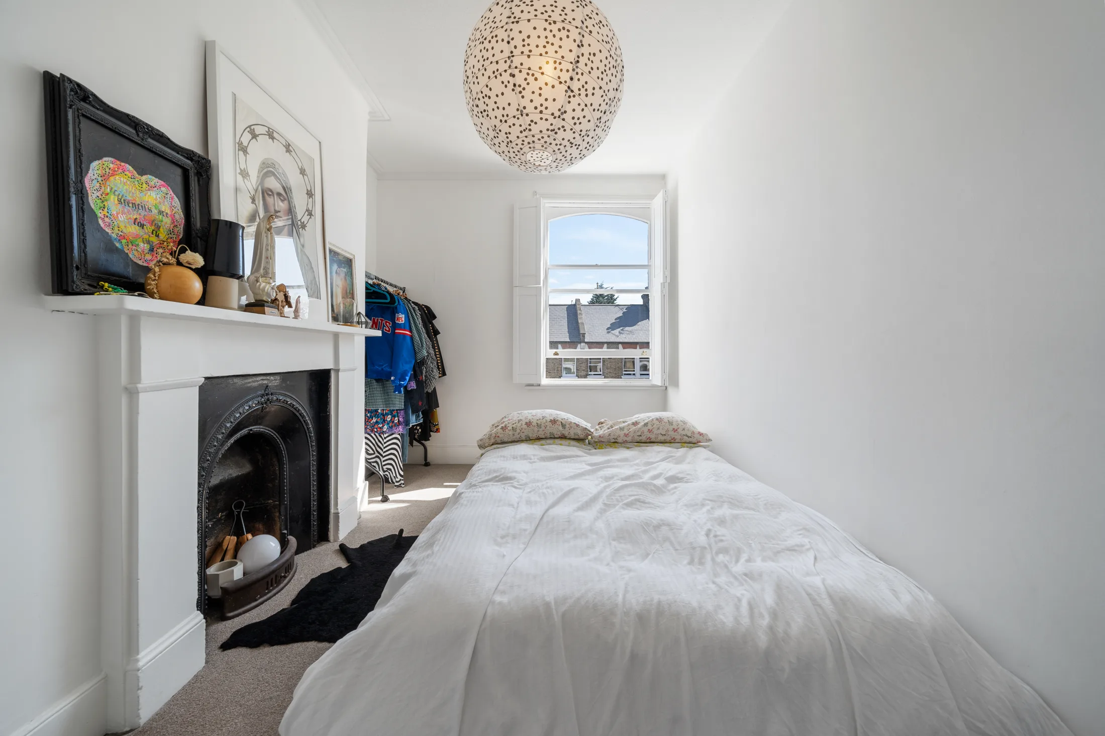 Bedroom with a white bed, fireplace and window