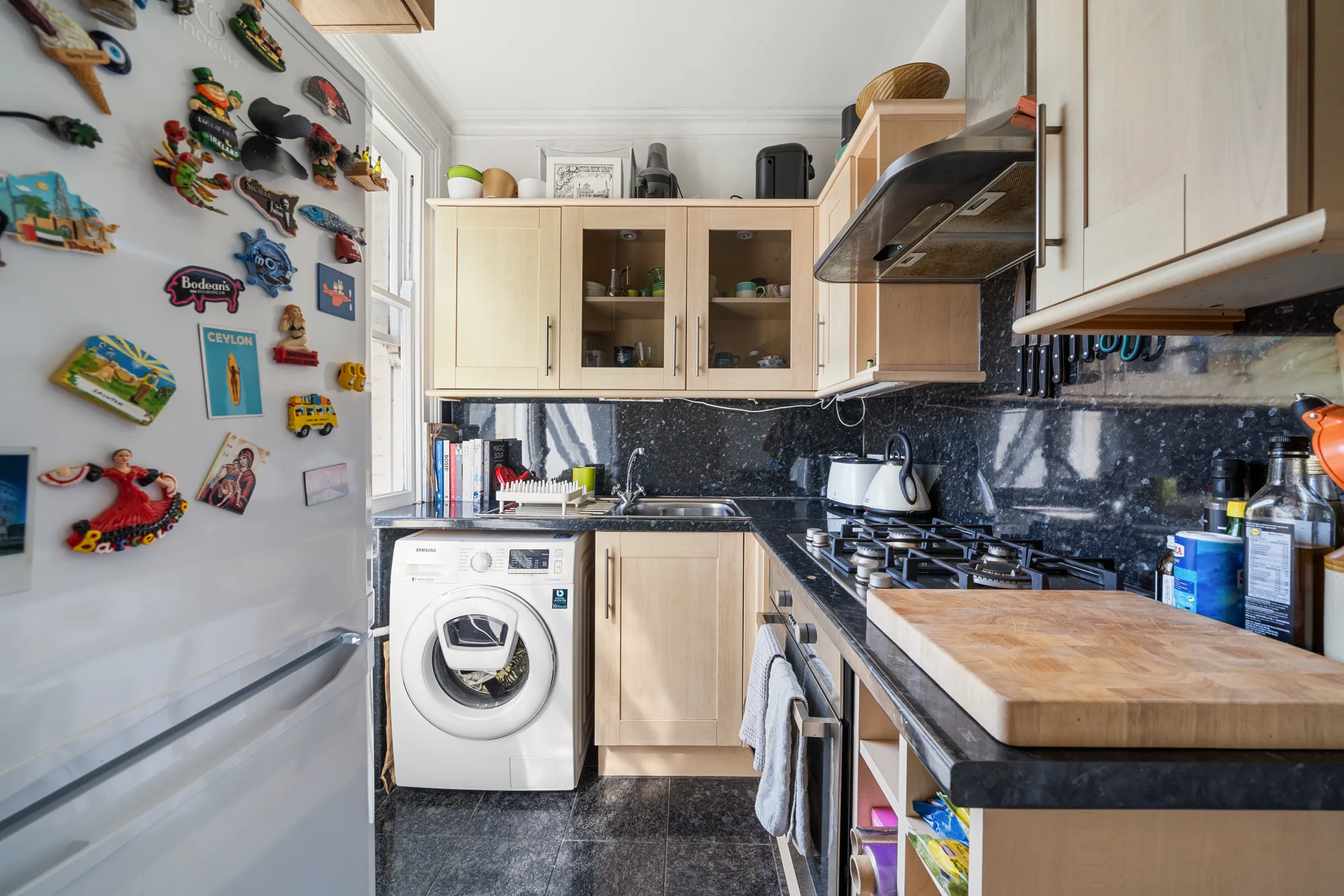 Fitted kitchen with light cabinetry and black worktops