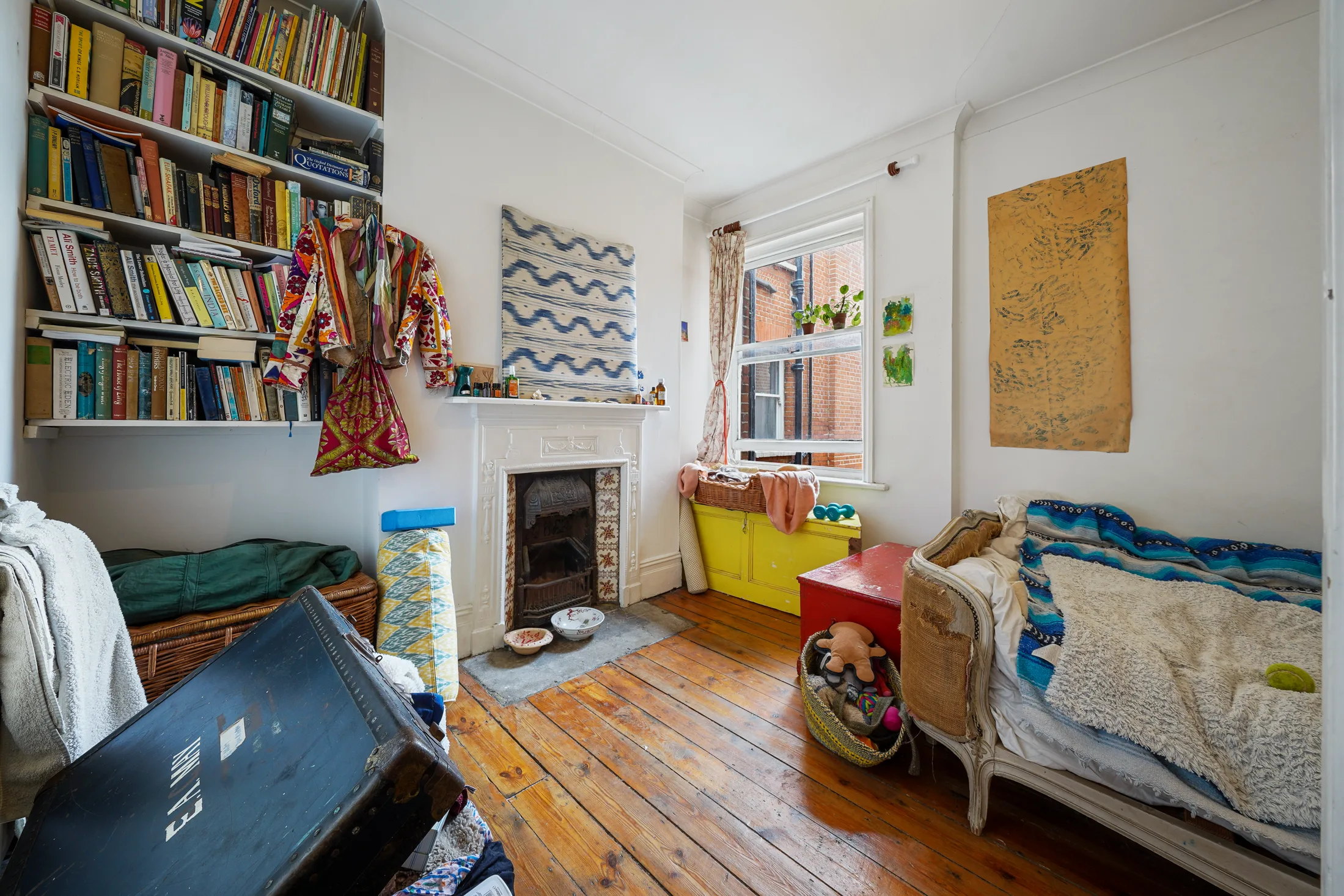 Bedroom with timber flooring, bookshelves and a bed
