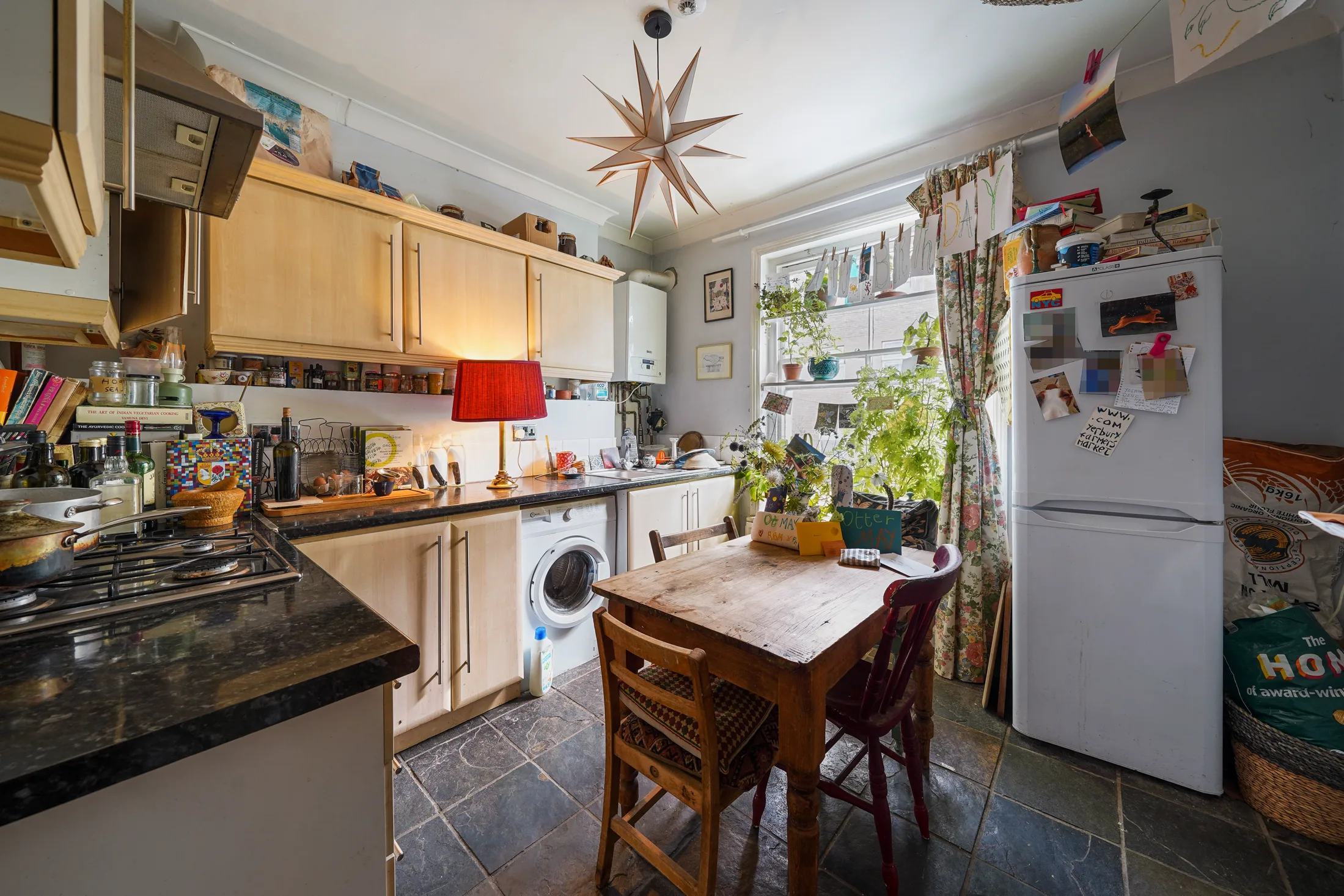 Fitted kitchen with pale cabinetry, appliances and a dining table