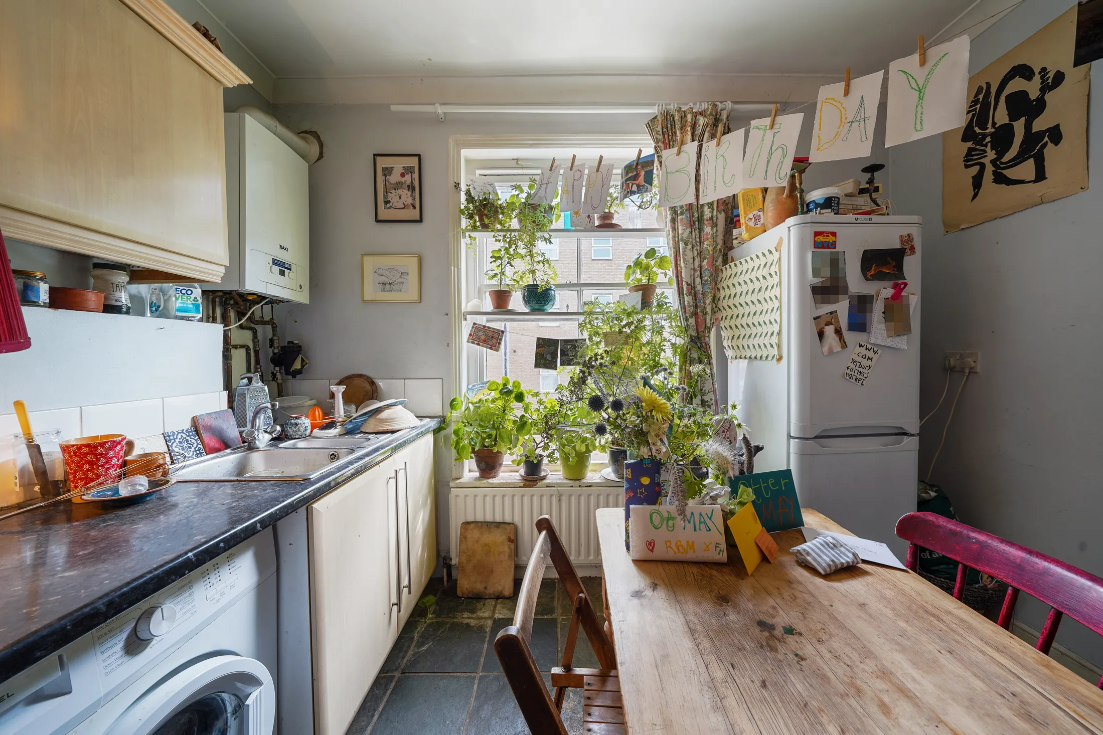 Kitchen with pale cabinetry, washing machine and dining table