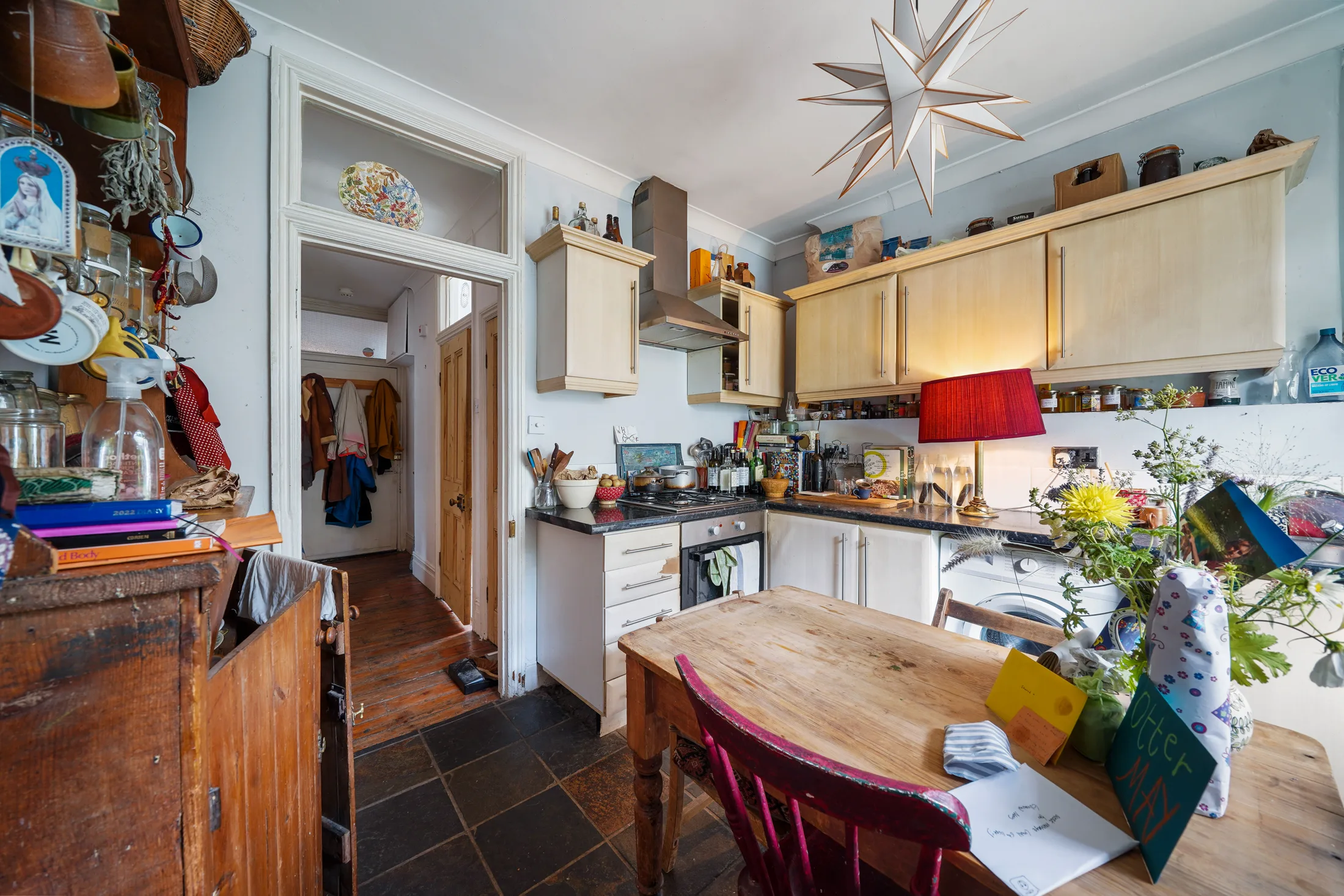 Fitted kitchen with pale cabinetry, cooker and dining area