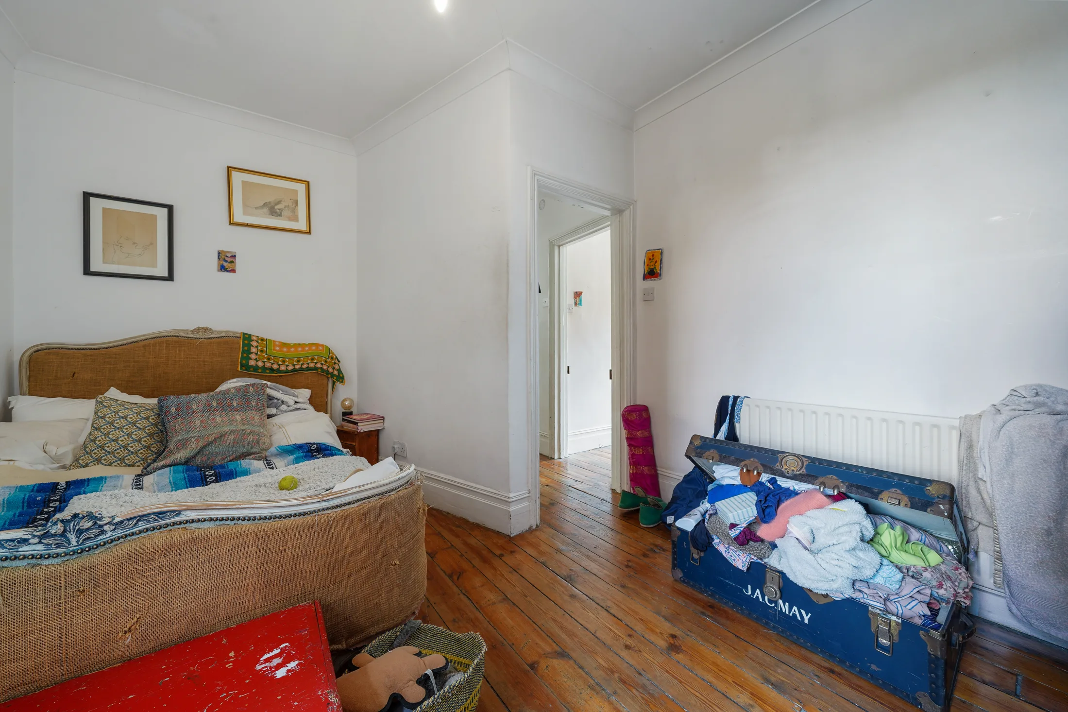 Bedroom with timber flooring, bed and wall-mounted artwork