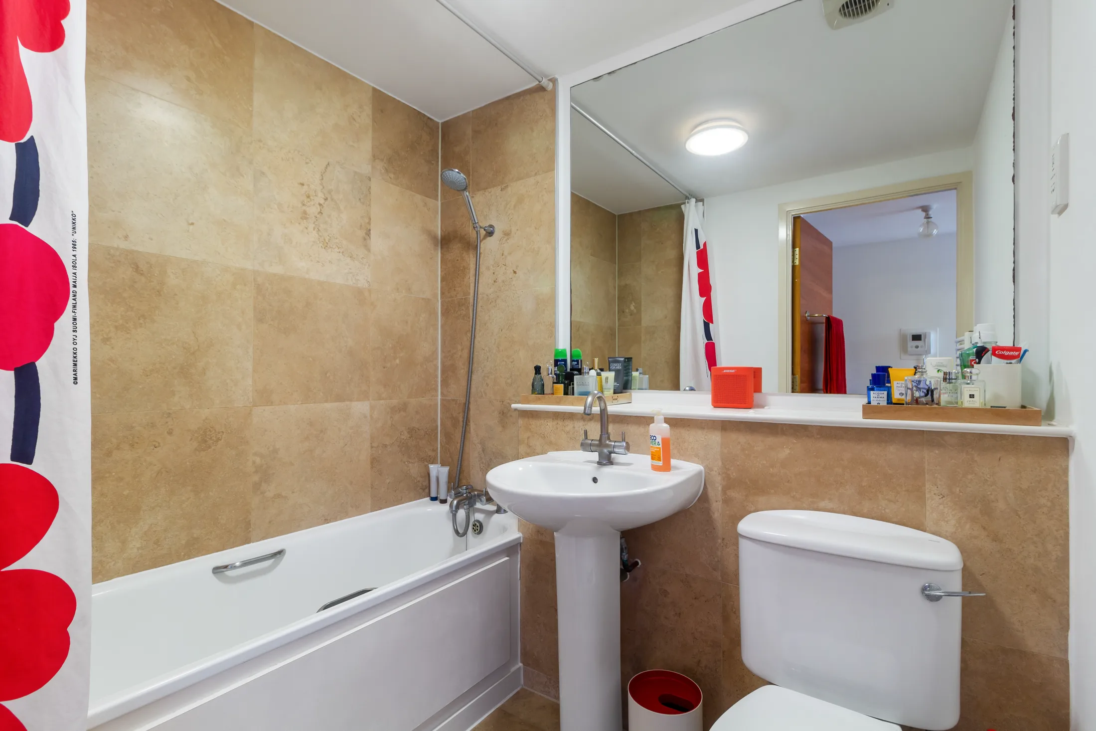 Bathroom with a bath, shower and tan tiled wall