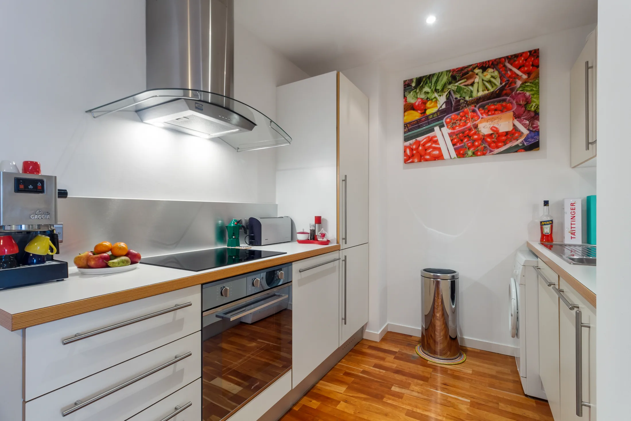 Fitted kitchen with stainless extractor, white cabinetry and timber flooring