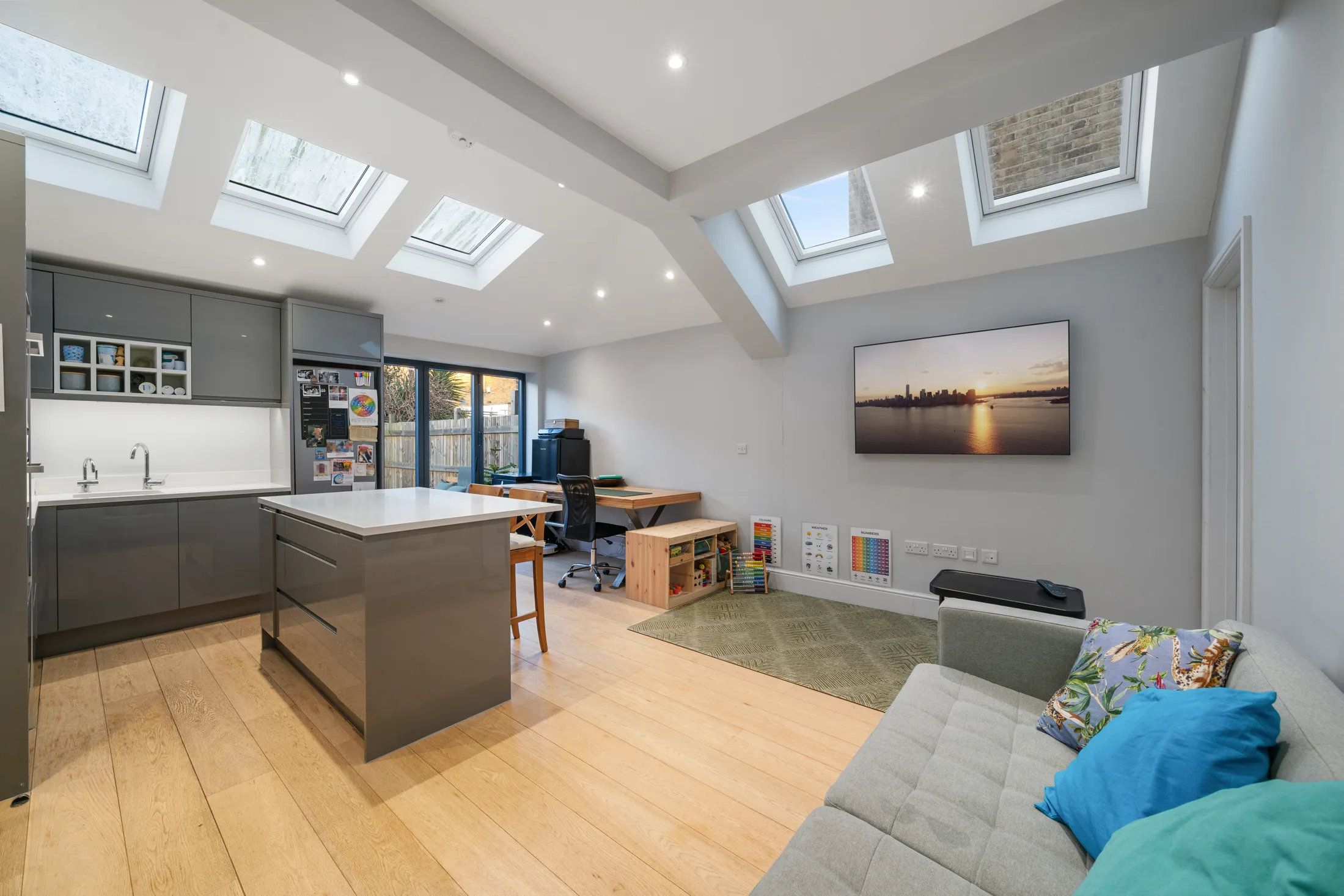 Open-plan reception and kitchen with skylights, island and sofa