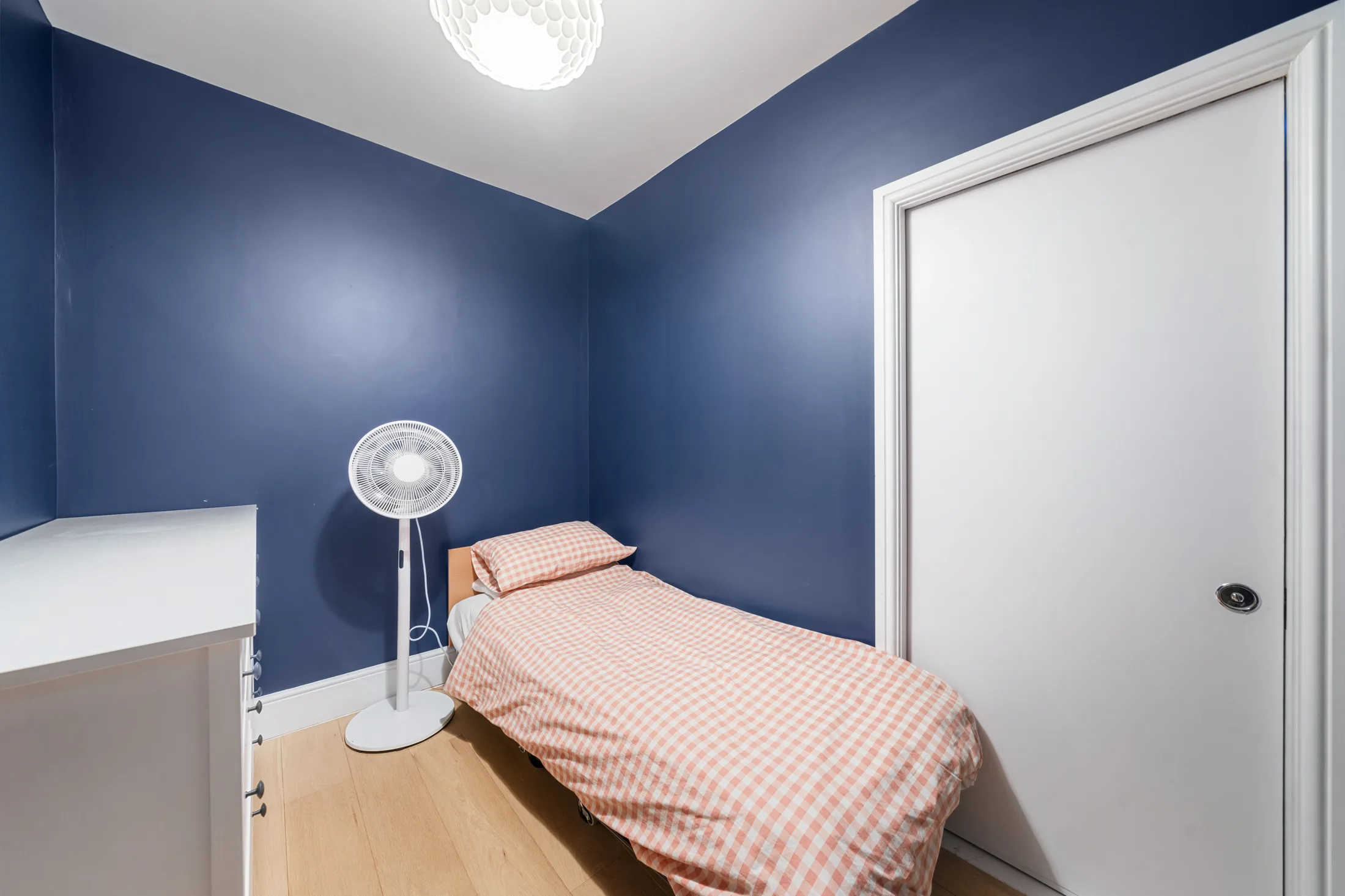 Bedroom with deep blue walls, single bed and white wardrobe
