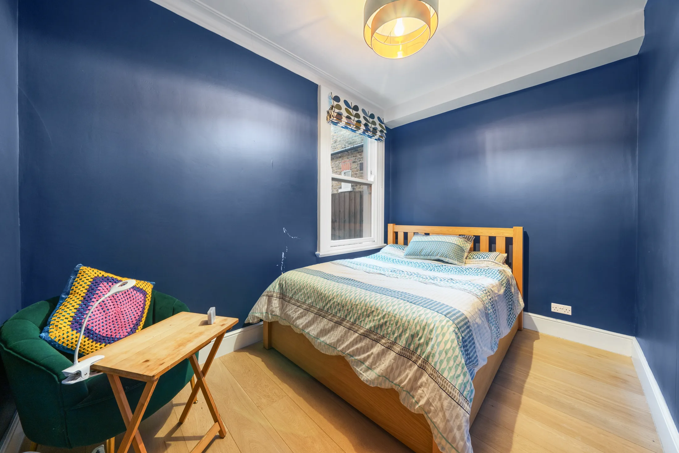 Bedroom with deep blue walls, double bed and armchair