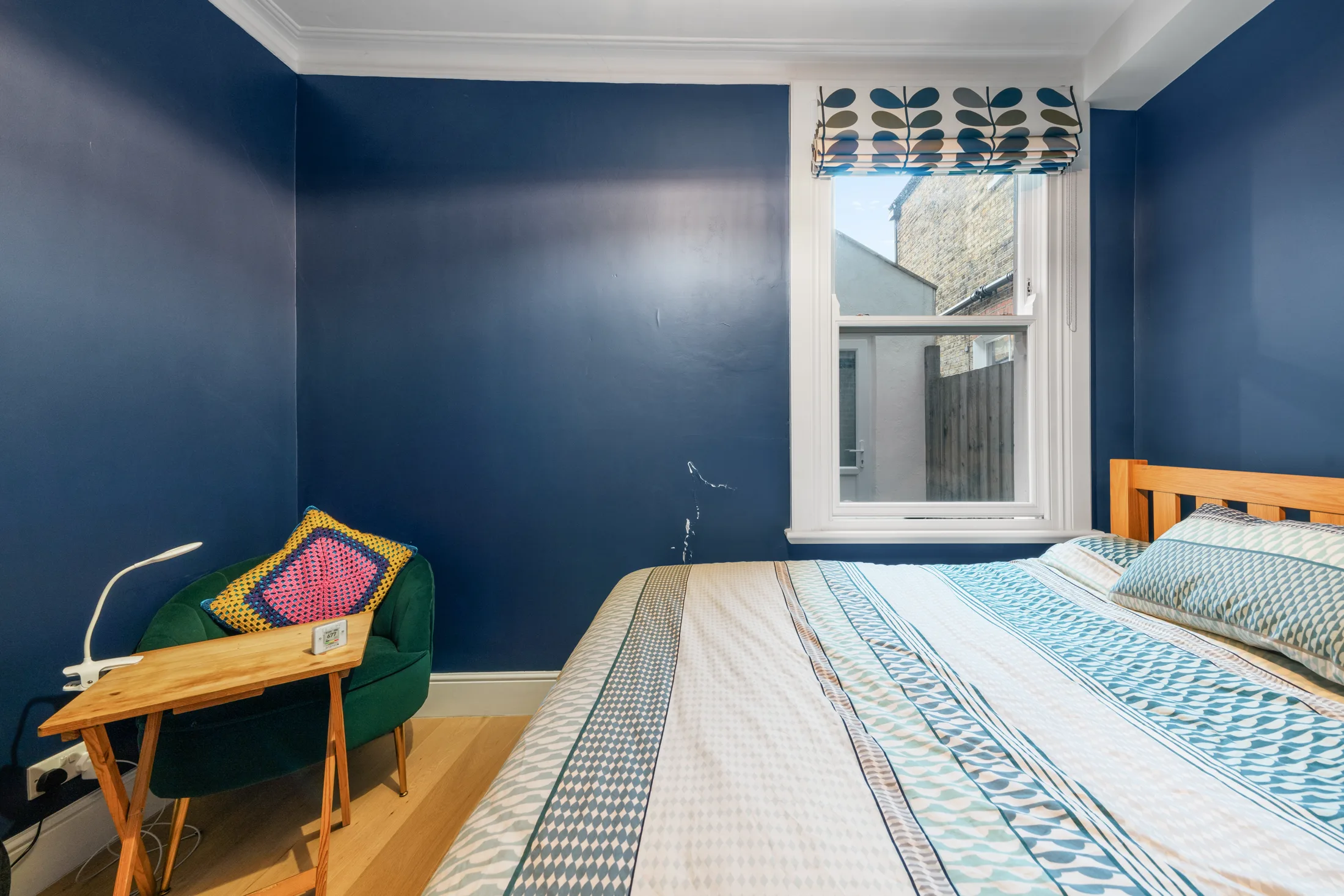 Bedroom with deep blue walls, double bed and window