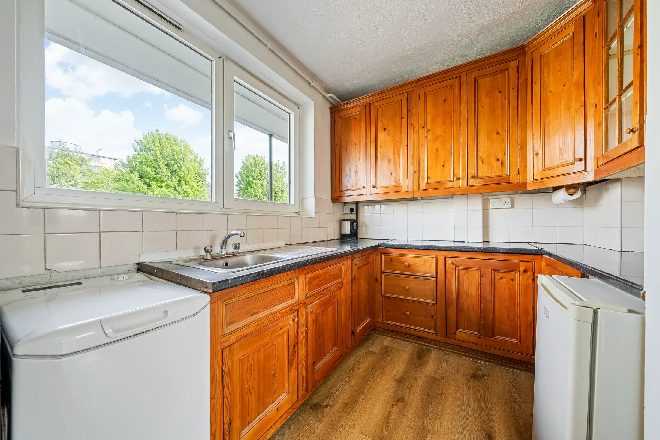 Fitted kitchen with pale cabinetry, tiled splashback and a window