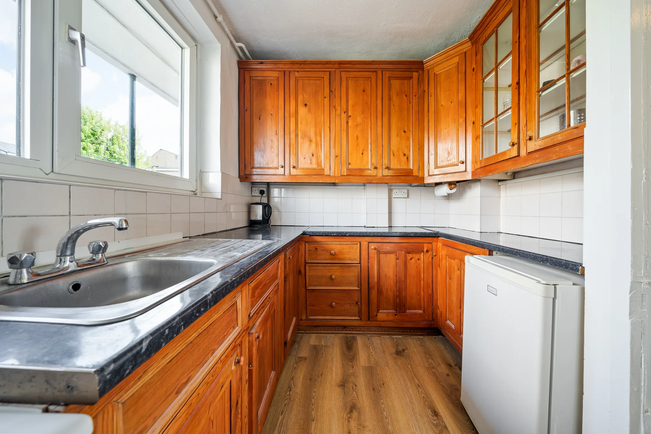 Fitted kitchen with pale cabinetry, appliances and a window