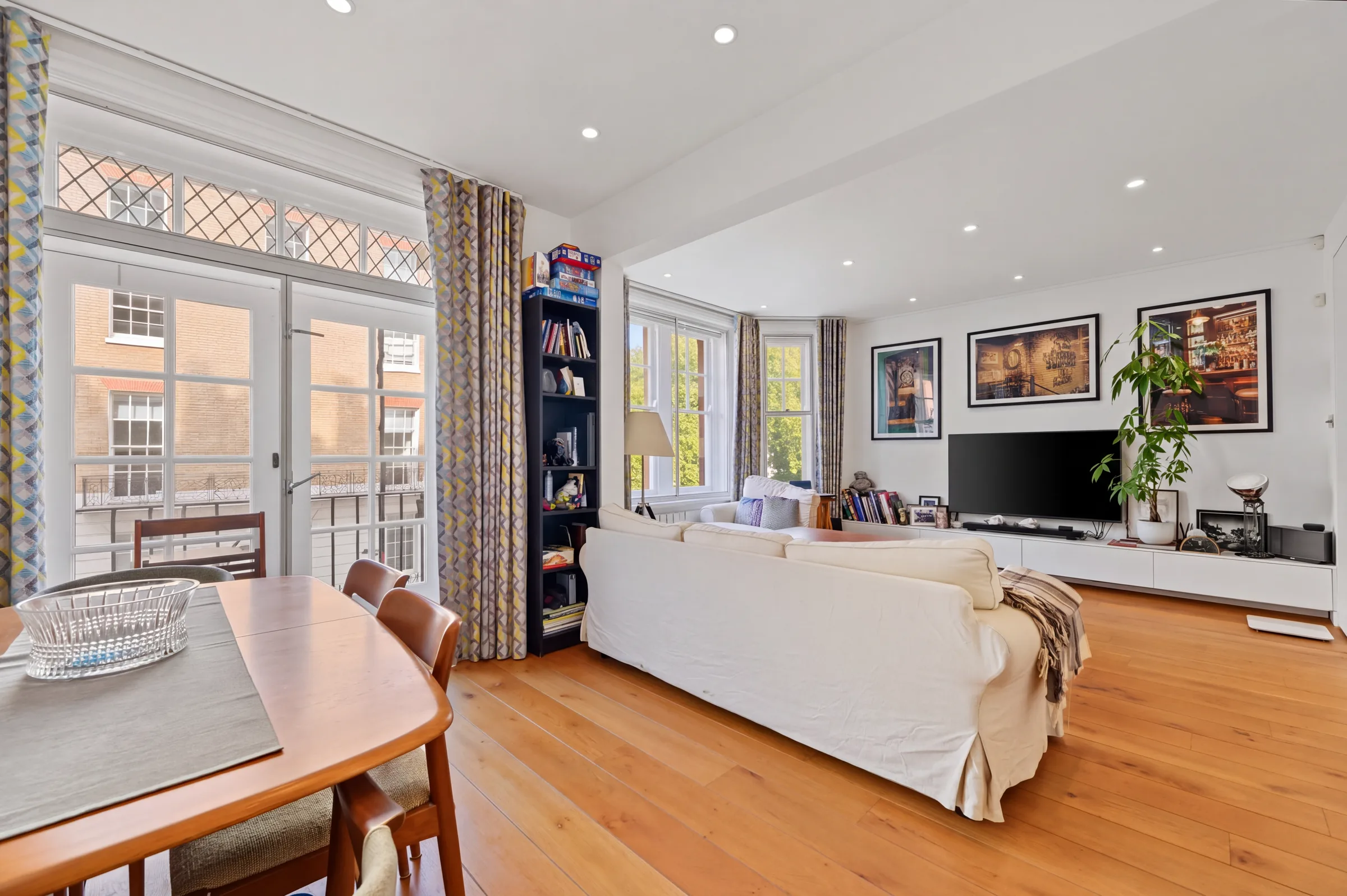 Reception room with oak flooring, dining area and balcony doors