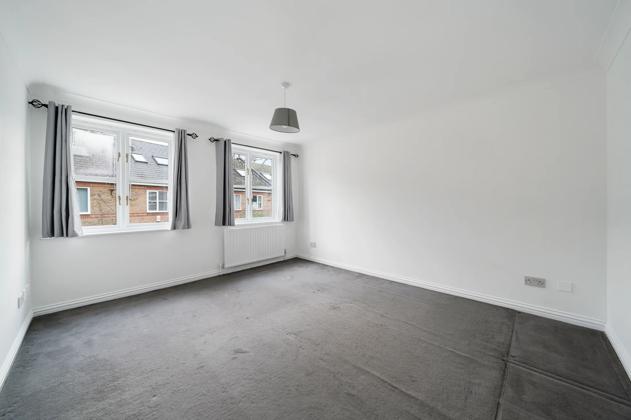 Bedroom with dark carpet and a curtained window