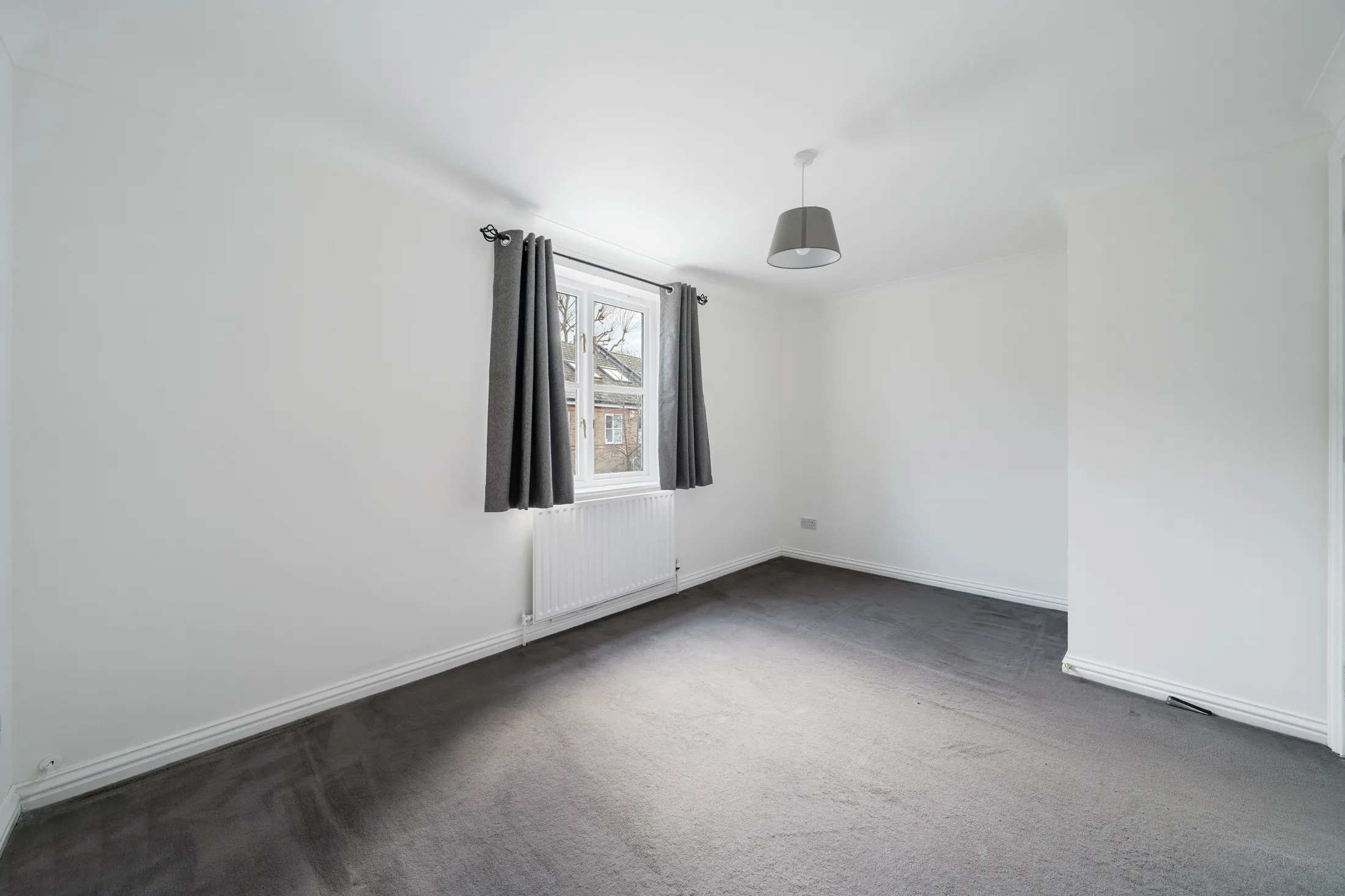 Bedroom with dark carpet, curtains and radiator
