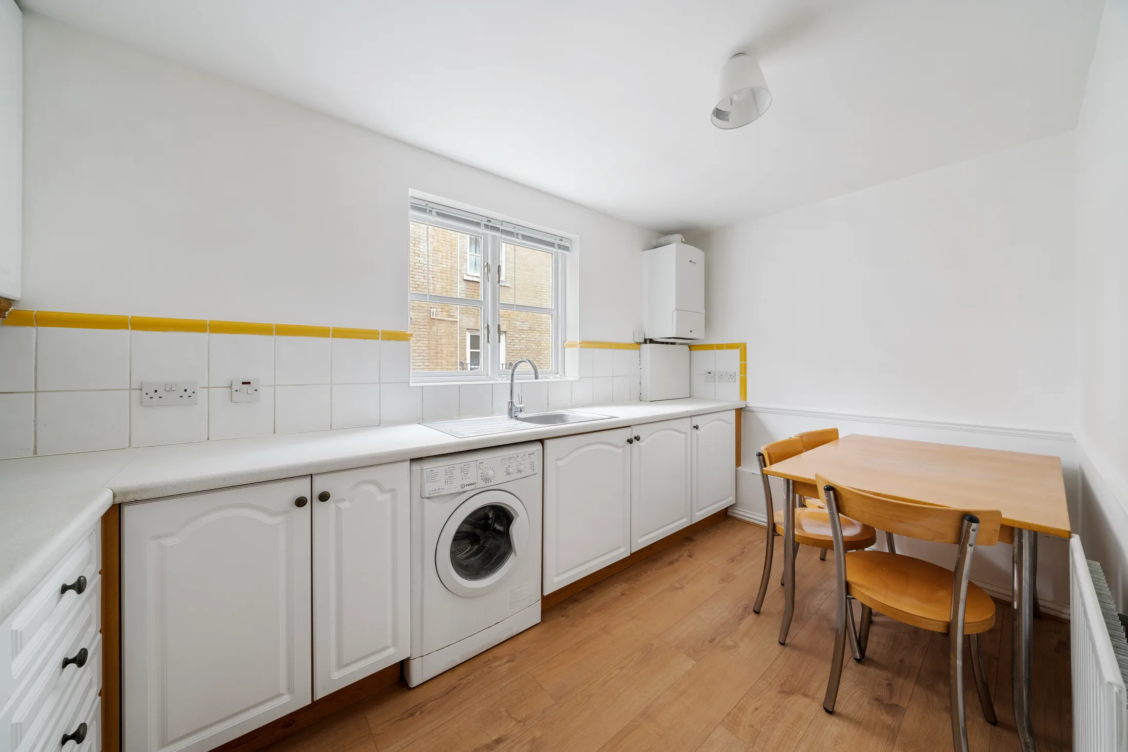 Fitted kitchen with white cabinetry, dining table and washing machine