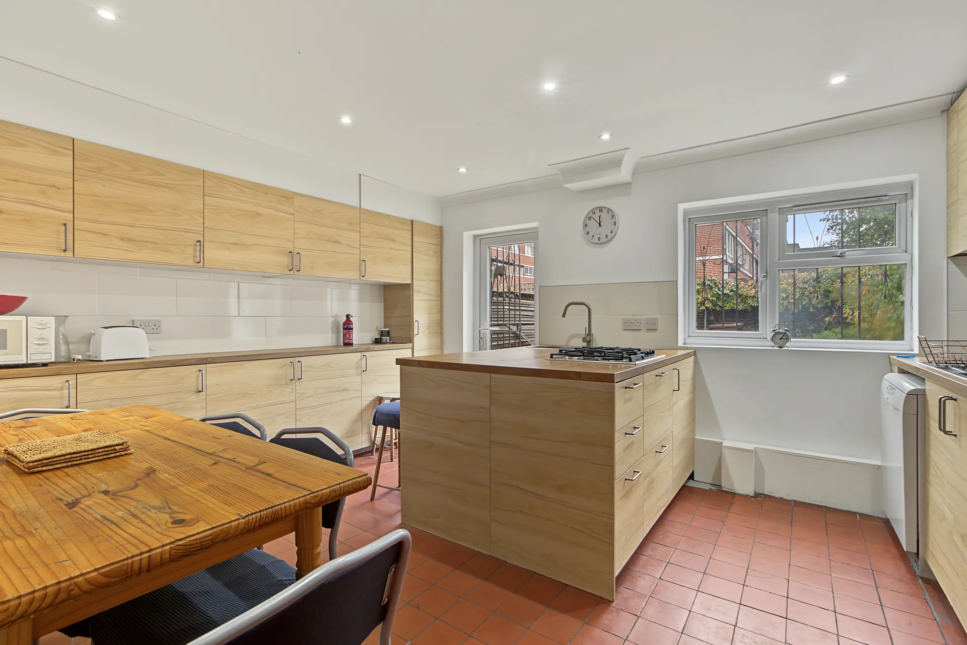 Kitchen and dining area with wood-effect cabinetry, a central island and a large dining table