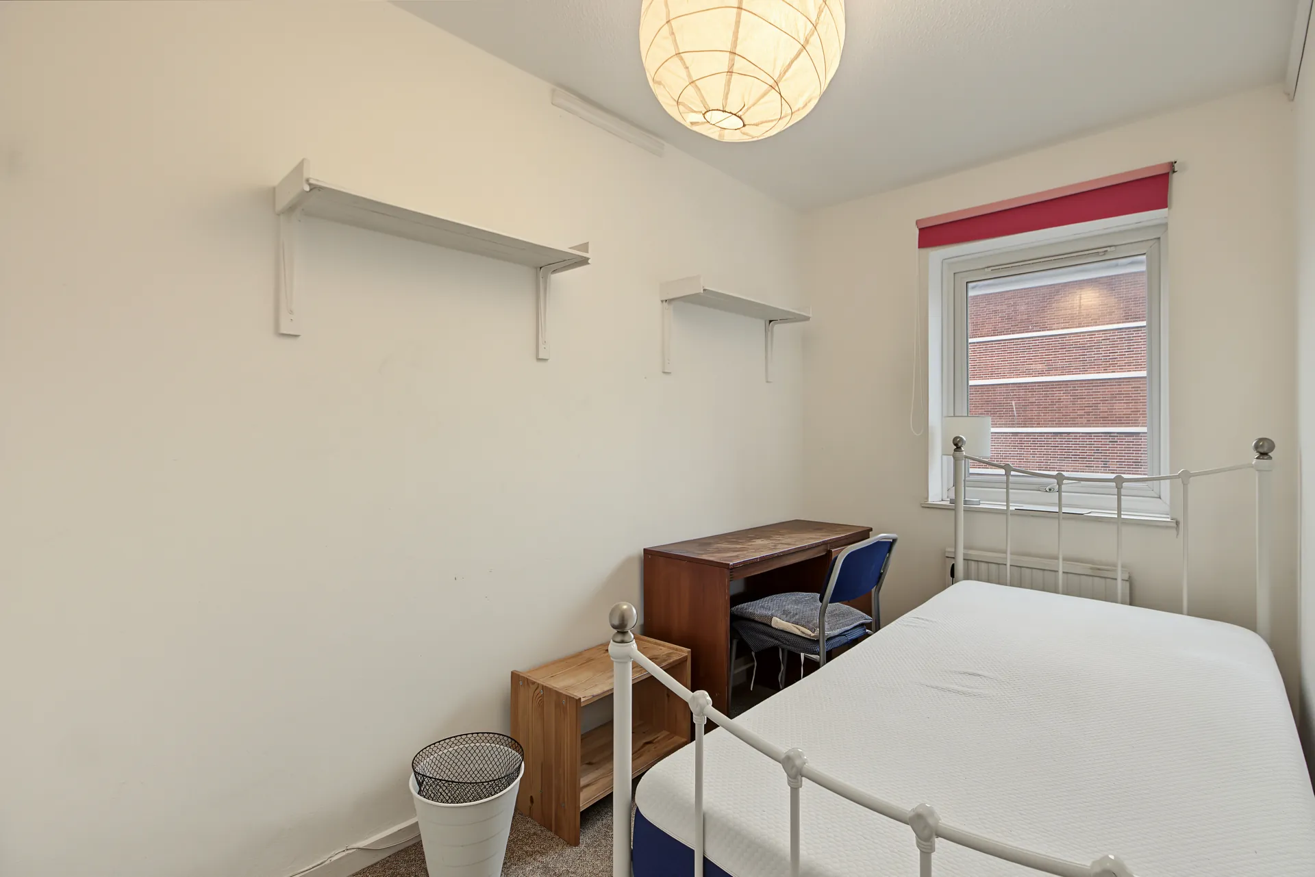 Bedroom with a window, desk and wall shelves