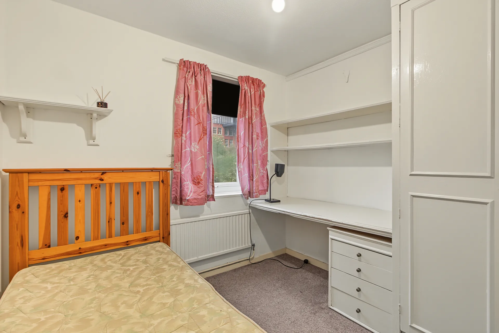 Double bedroom with a wooden bed, desk and built-in storage