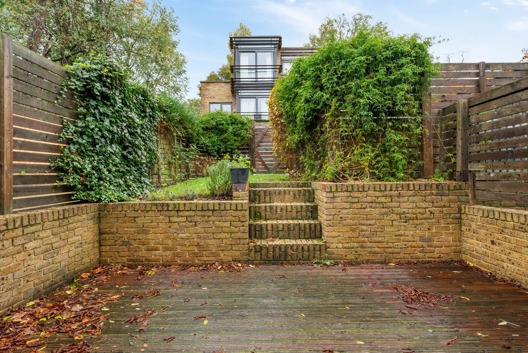 Paved garden with raised planting bed and timber fencing