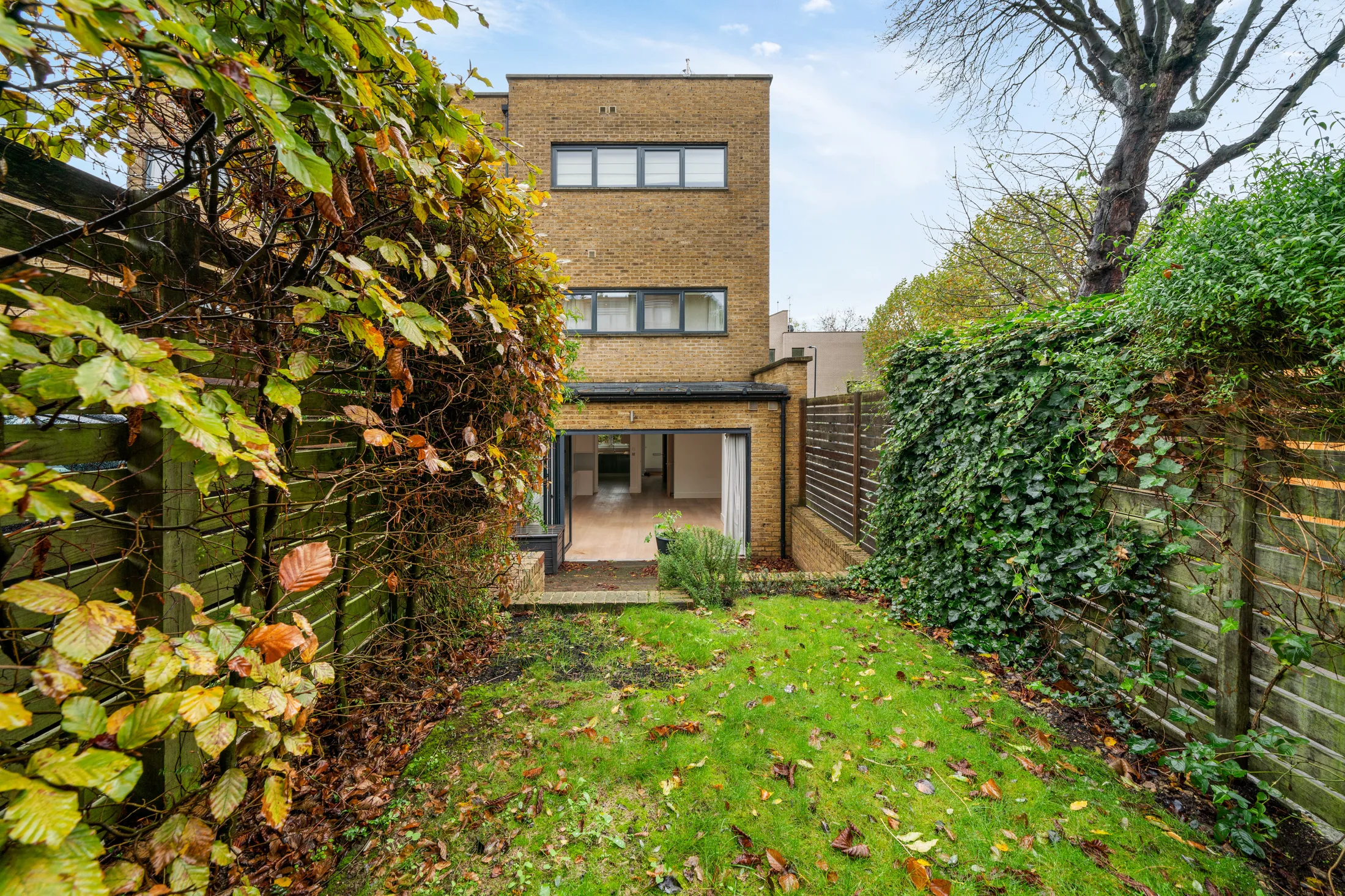 Rear garden with lawn, planting and surrounding brick walls
