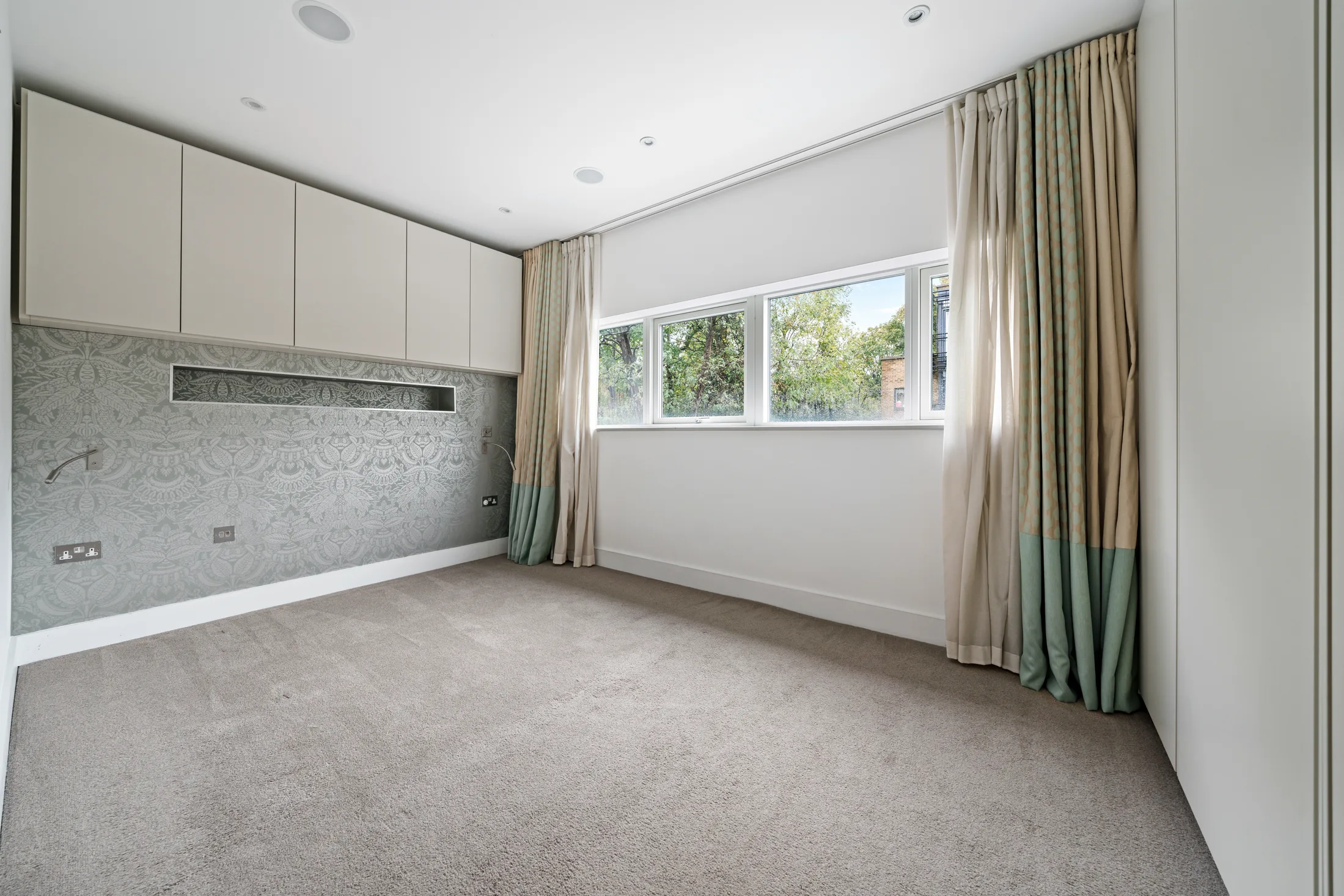 Bedroom with fitted wardrobes, carpet and large window