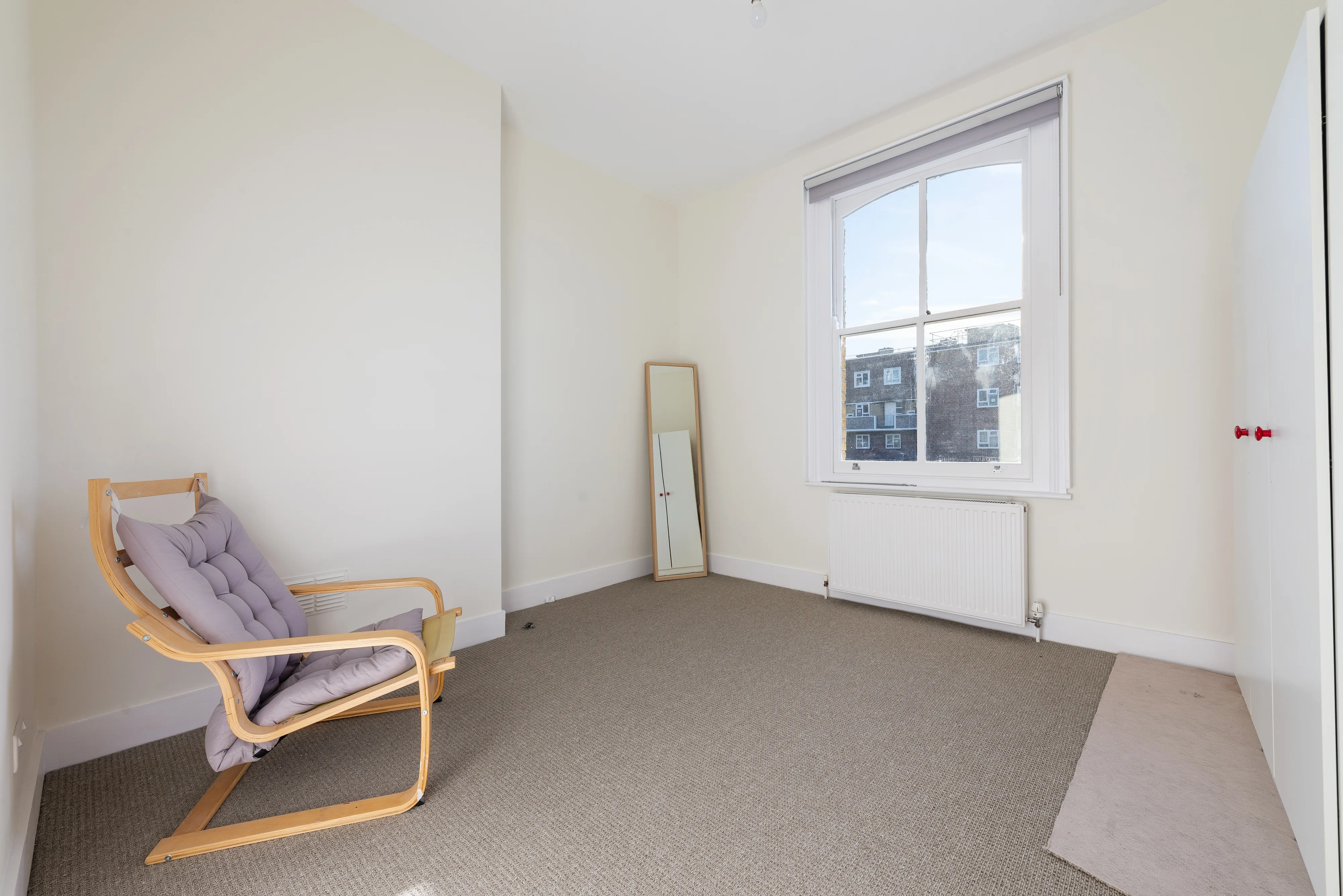 Reception room with a fireplace, large window and neutral carpet