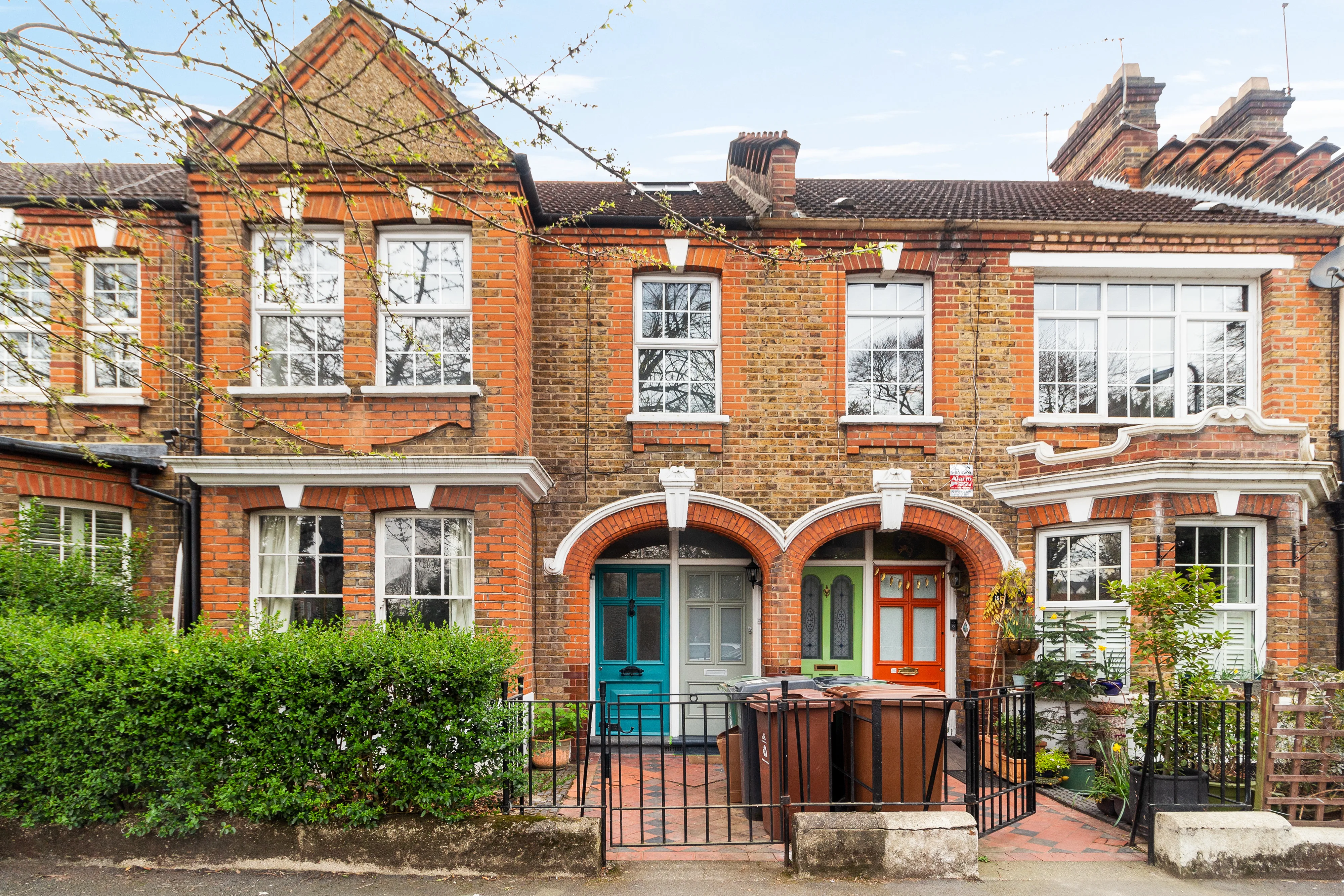 Red-brick terrace frontage with planted gardens and front doors