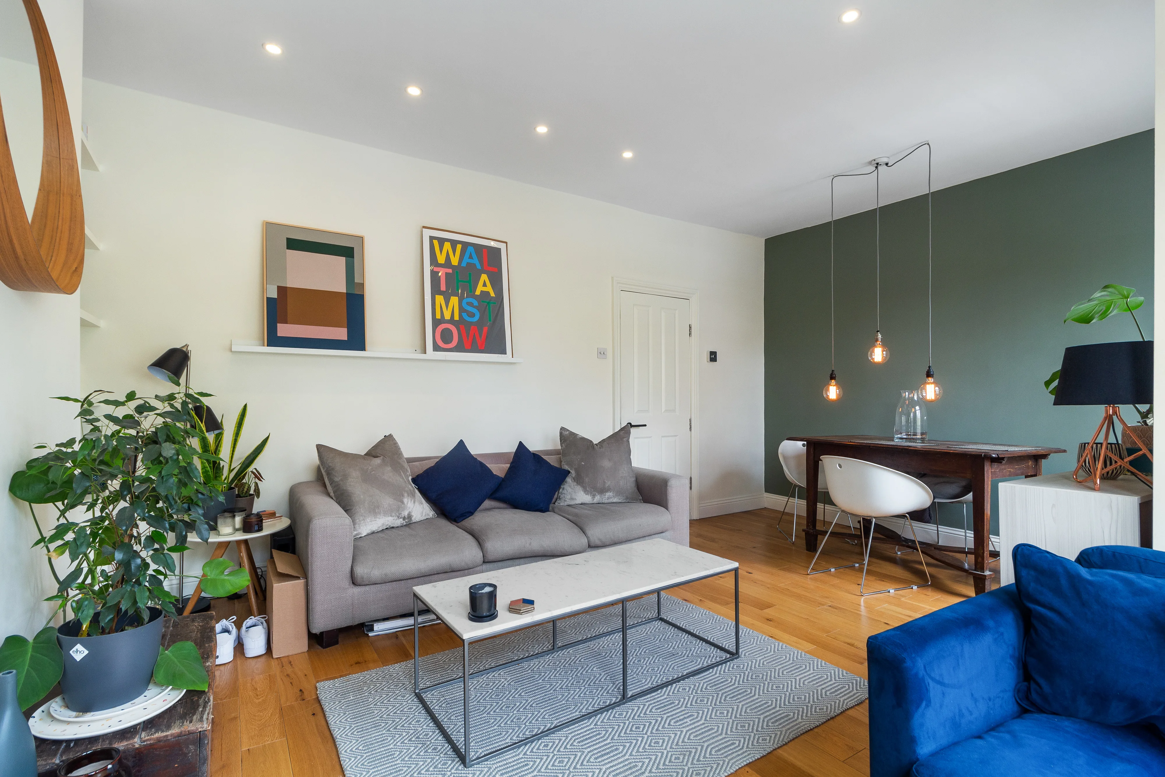 Reception room with a sofa, dining table, bookshelves and timber flooring