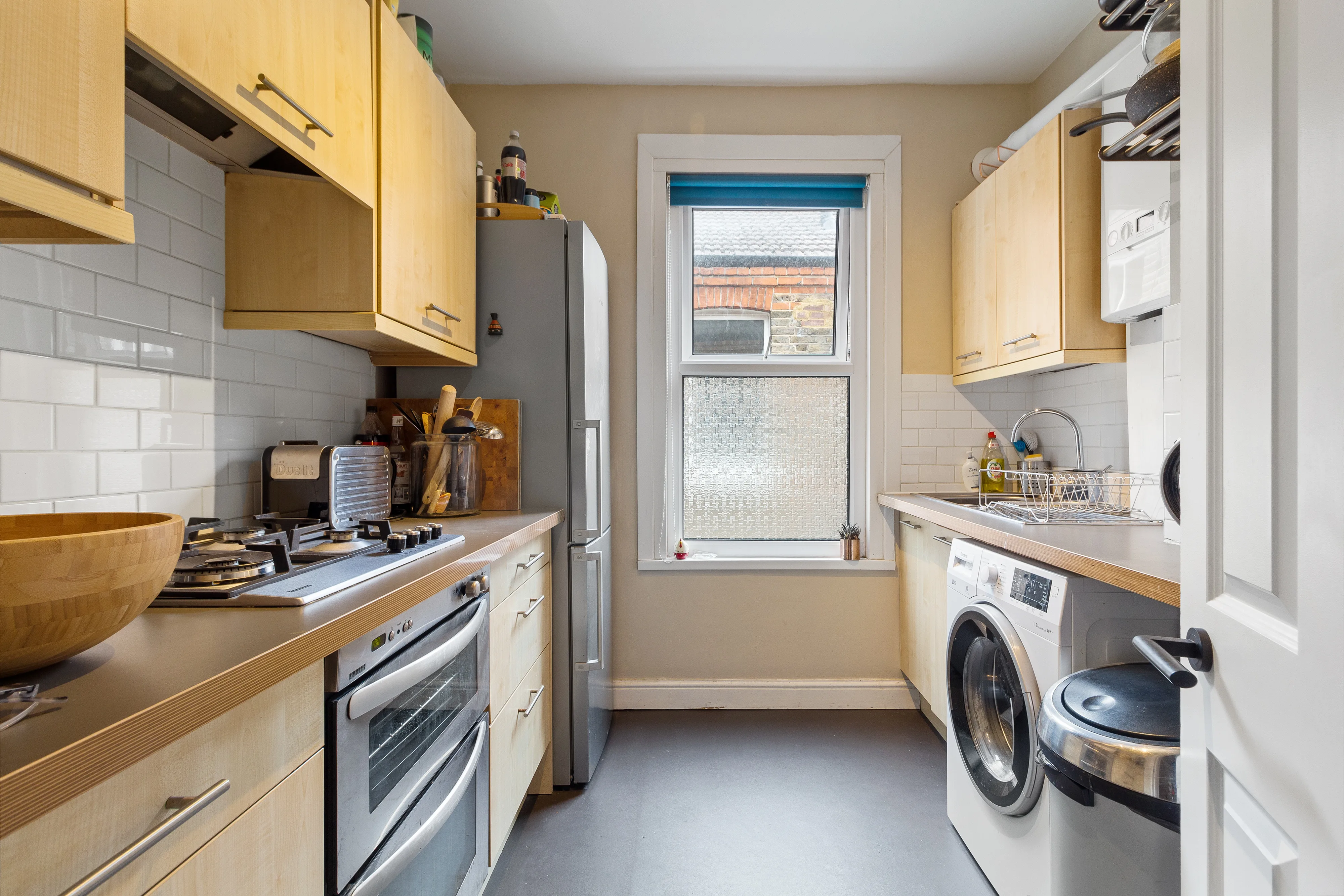 Fitted kitchen with timber cabinetry, tiled splashbacks and a window