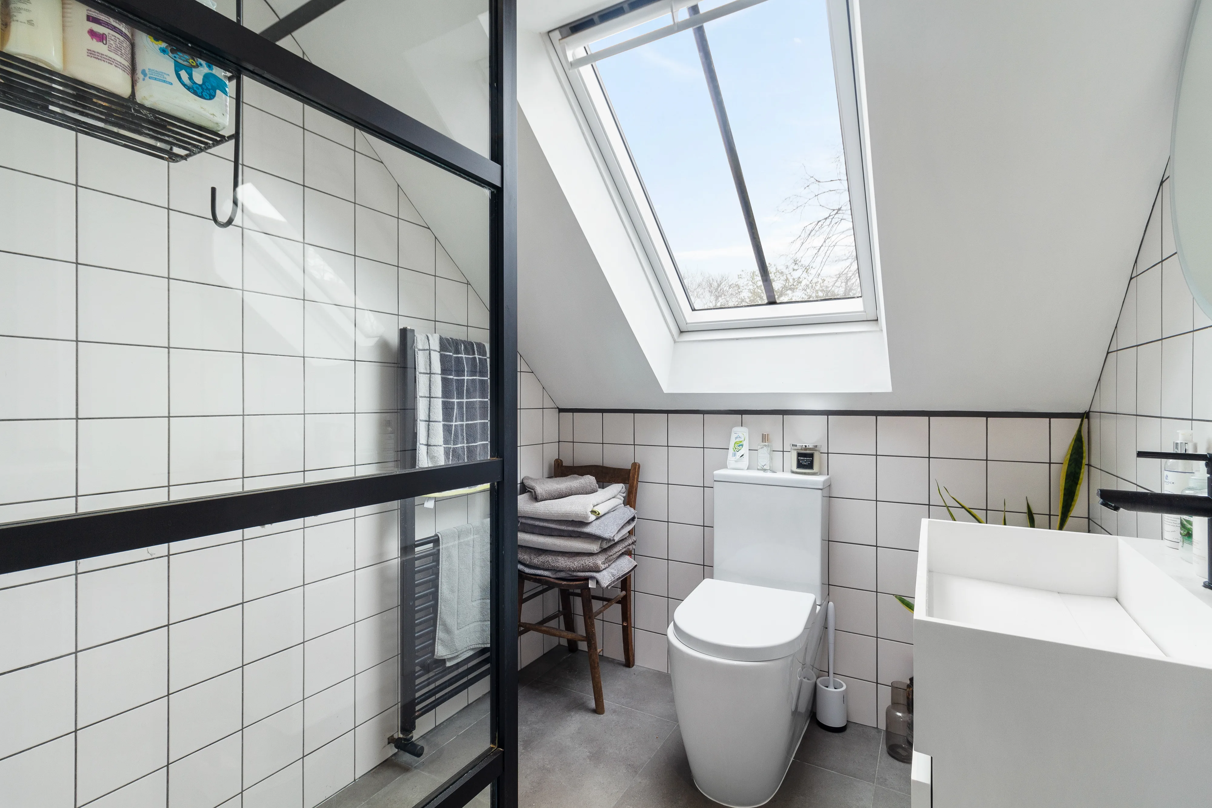 Shower room with a skylight, glass enclosure and white tiled walls